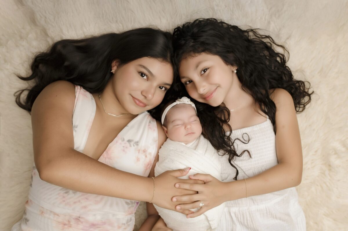 sisters holding wrapped newborn in Bel Air photography studio - Sugarloaf Photography